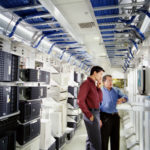 Two businessmen using computer in server room
